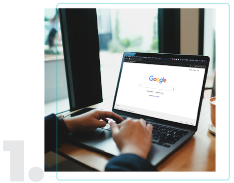 person is typing on Google search engine from a laptop.